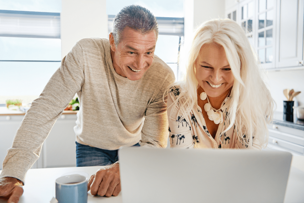 Happy old couple looking at laptop screen